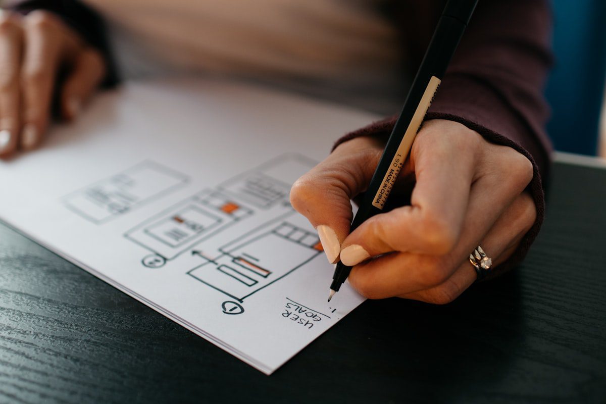 Main dessinant le wireframe d'une page web au stylo